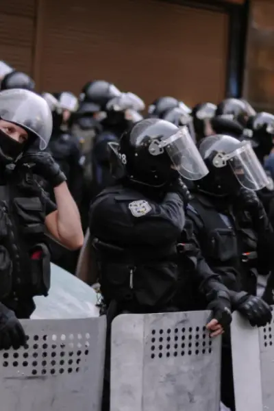 Un gruppo di poliziotti in assetto antisommossa con caschi e scudi fermi in attesa