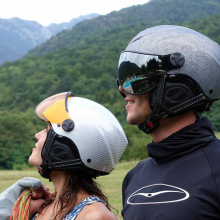 due giovani bikers di profilo in mezzo la natura. a sinistra, una ragazza con il casco bianco e visiera alzata gialla trasparente. a destra, un ragazzo con visiera nera abbassata e casco grigio argento