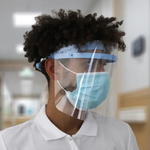 Ragazzo riccio indossa una visiera sanitaria protettiva